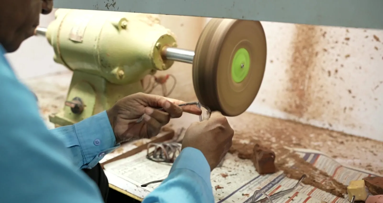Craftsman hand polishing an acetate frame on a rotary buffing wheel